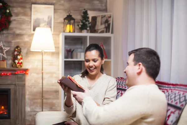 Excited young woman while her husband is giving her a gift — Stock Photo, Image