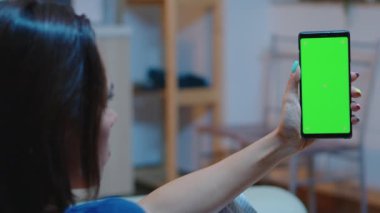 Ev hanımı elinde yeşil ekranlı akıllı telefon tutuyor.