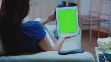 Elinde yeşil ekranlı bir tablet tutan genç bayan.