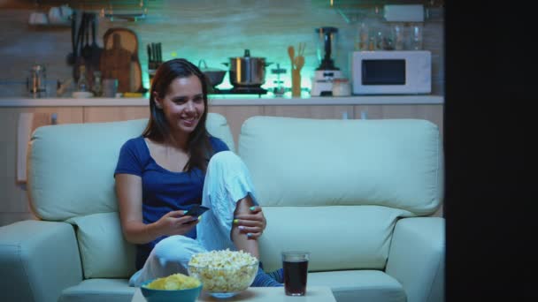 Vrouw die popcorn eet op de bank — Stockvideo
