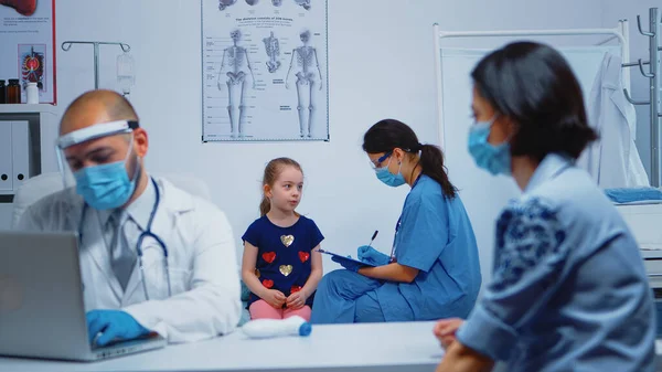 Verpleegkundige die kindgegevens op klembord schrijft — Stockfoto