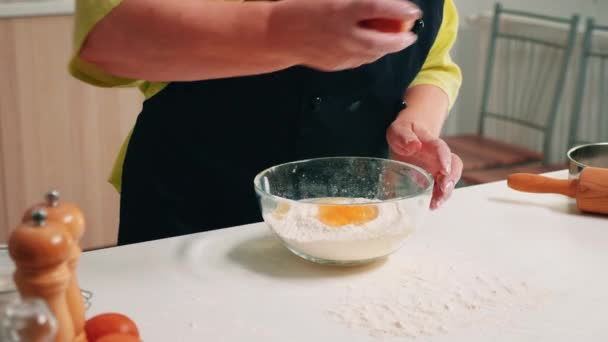Close-up van handen vrouw het toevoegen van eieren in bloem — Stockvideo