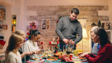 Baba bir şişe şarap açarken heyecanlı aile fertleri