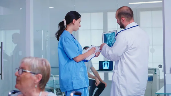 Personnel médical tenant le comprimé pc avec radiographie du patient dans le couloir de l'hôpital — Photo