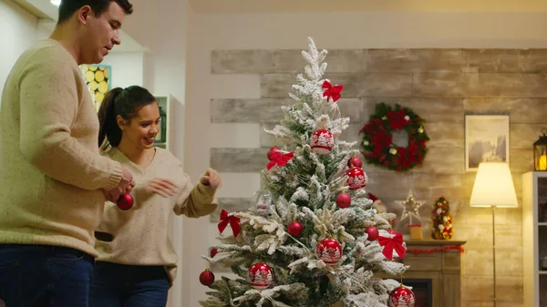Пара с подходящей одеждой украшают рождественскую елку — стоковое фото