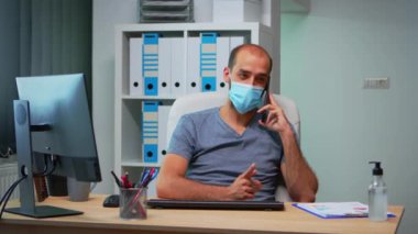 Maskeli Freelancer cep telefonuyla konuşuyor