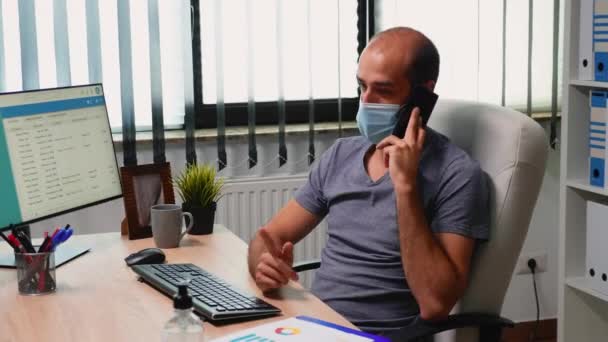 Arbetare med ansiktsmask pratar i telefon — Stockvideo