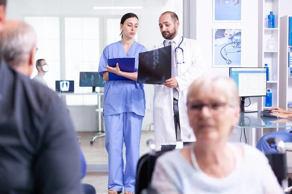 Медсестра дивиться на рентгенографію під час розмови з лікарем — стокове фото