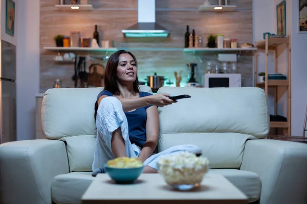 Жінка сидить на дивані і дивиться телевізор — стокове фото