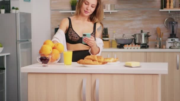 Sexy huisvrouw met behulp van smartphone — Stockvideo
