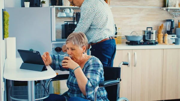 Vrouw in een rolstoel met tabletcomputer — Stockfoto