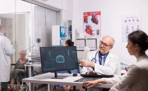 Médecin aux cheveux gris pointant vers la radiographie — Photo