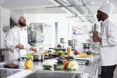 Çeşitli şefler bir restoranda yemek hazırlamak için sebze ve otları dilimliyor, taze ürünler ve lezzetli bir gurme yemeği yapmak için yüksek kaliteli malzemeler kullanıyorlar. Gastronomi endüstrisi.