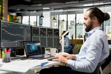 Bilgisayarda otomatik ticaret ve portföy dengeleme için yapay zeka destekli aletler kullanan bir tüccar. Karmaşık pazar verilerini analiz etmek için dizüstü bilgisayar yazılımı kullanarak derin öğrenme algoritmaları uygulayan adam