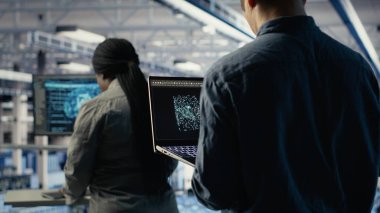 Veri merkezindeki yazılım geliştiricisi, rutin sistem incelemesi sırasında dizüstü bilgisayarı kullanarak Al 'ın gösterge panelini kontrol ediyor. Sunucu merkezi IT uzmanı performansı kontrol etmek için yapay zekayı not defterinde test ediyor, kamera B