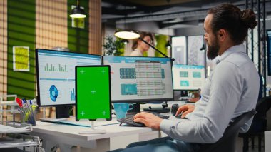 Erkek yönetici grafikler ve izole edilmiş maket ekran ile çalışarak uluslararası piyasada iş başarısı sağlıyor. Ofisteki küresel genişleme stratejisi için veriler gözden geçiriliyor.