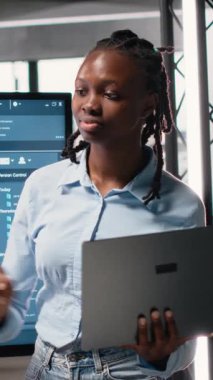 Dikey Video Siyah Kadın Mühendis, kentsel bir bölgedeki bir konut projesinde proje onayı için dijital yapı planlarını, belge hazırlama ve imar düzenlemelerini gözden geçiriyor