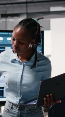 Dikey Video Afrikalı Amerikalı erkek müteahhit, şehir merkezindeki bir konut projesinin proje onayı için ayrıntılı yapı planları ve planlarını, belgeleri inceliyor.