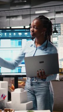 Dikey Video Siyah Kadın Mühendis, kentsel bir bölgedeki bir konut projesinde proje onayı için dijital yapı planlarını, belge hazırlama ve imar düzenlemelerini gözden geçiriyor