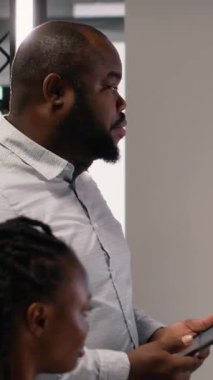 Dikey Video Afrikalı Amerikalı emlak mühendisi ekiple işbirliği sırasında 3D modeller üzerinde site hazırlama planı ve imar düzenlemelerini sunuyor. Şehir planlaması için konut girişimi