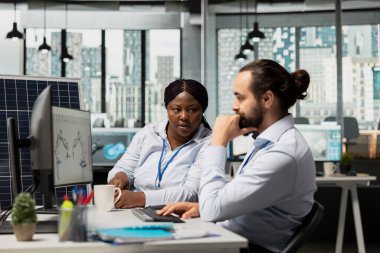 Mühendislerden oluşan bir ekip, karbon ayak izi tasarımlarıyla güneş paneli hücrelerine beyin fırtınası yapıyor. Ofisteki takım arkadaşları otomatik temiz enerji güneş paneli üretimi için robotik kol sistemleri geliştiriyorlar.