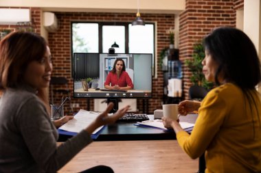Dosyaları olan Asyalı kadınlar, bilgisayar başında Kafkasyalı yöneticiyle görüntülü görüşme yapıyorlar, iş başvurularının özgeçmişlerini gözden geçiriyorlar. Bir toplantı için dijital iletişimi kullanan kadın başlangıç takımı.