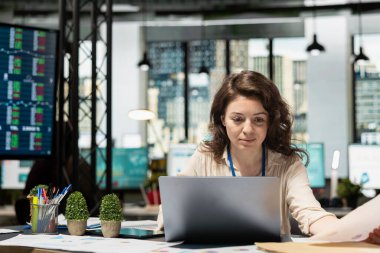 Genel müdür masasında tek başına detaylı bir iş stratejisi hazırlıyor, çok uluslu şirket büyümesi ve genişlemesi için verimli bir vizyon geliştiriyor. Veri analizlerini gözden geçiren güçlü bir kadın.