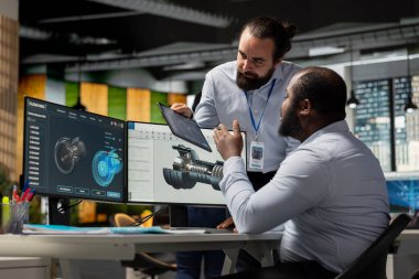 Yönetici ve araştırmacı birlikte çalışarak sürdürülebilirlik ölçümlerini geliştirmek için türbin bileşenlerini analiz ediyor. Yeşil teknoloji şirketi lideri ve iş arkadaşı türbin parçalarını emisyonları azaltmak için modifiye ediyor