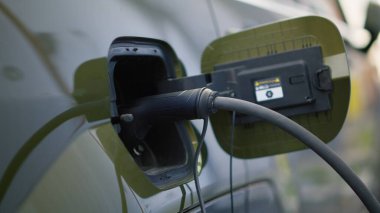 Otoparktayken EV çevre dostu arabanın şarj edilişini yakından çek. Yenilenebilir enerjiyi emisyonsuz olarak kullanarak şarj edilebilir pille donatılmış elektrikli araç takın
