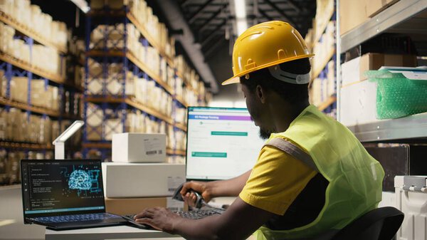 Black employee works with AI tools to enhance package tracking efficiency, using machine learning and parcel tracking info to ensure seamless distribution operations in warehouse. Camera A.
