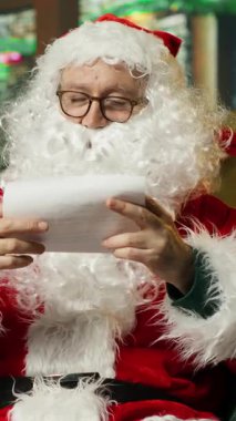 Noel Baba 'nın hediye kutusunu aldığı dikey video, Noel seti içinde çocukların mektuplarını okurken çekilmiş. Dilek listelerine bakarken erkek kucağına düşmek, Noel mucizesi konsepti