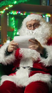 Noel Baba 'nın hediye kutusunu aldığı dikey video, Noel seti içinde çocukların mektuplarını okurken çekilmiş. Dilek listelerine bakarken erkek kucağına düşmek, Noel mucizesi konsepti