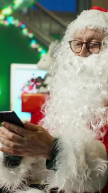 Dikey Noel Baba videosu tatillerde çocuklarla telefonda konuşarak diğerlerine neşe veriyor. Noel Baba cep telefonunu kullanarak Noel 'de merak duygusu yayıyor, telefon görüşmesi yapıyor.