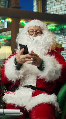 Dikey Noel Baba videosu tatillerde çocuklarla telefonda konuşarak diğerlerine neşe veriyor. Noel Baba cep telefonunu kullanarak Noel 'de merak duygusu yayıyor, telefon görüşmesi yapıyor.