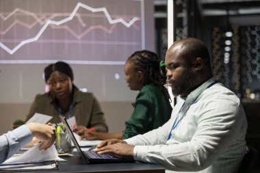 Çeşitli çalışanlar, küresel iş gelişimini kolaylaştırmak için analitik pazar eğilimlerini inceleyerek, gece yapılan bir şirket toplantısında yıllık veri raporlarını inceliyor. Çalışma ekibi planlaması.