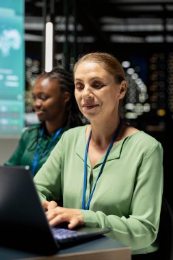 Kadın danışman, hedef belirleme ve girişim hedefleri için veri tahminleri ve ekonomik analizleri kullanarak, dizüstü bilgisayardaki finansal güncellemeleri ve hedefleri izliyor. Geceleyin proje genel görünümü.