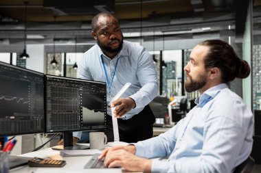 Ekip çalışanları malzeme firmasında çalışıyor. Beyin fırtınası yapıyor, bilgisayar üzerinden ticaret uygulaması kullanıyor. Yatırım fonu çalışanları ve tekerlekli sandalyedeki engelli kişi borsa verilerini izliyor