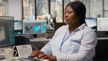 Gülümseyen mühendisin portresi temiz enerji teknolojisiyle güneş enerjili cihaz tasarımı yapmak için PC kullanıyor. Ar-Ge ofisindeki mutlu Afrikalı Amerikalı kadın ekolojik güneş aygıtı prototipi, kamera B 'yi yaratıyor.