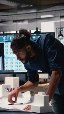 Dikey Video Ortadoğu mühendisi dizüstü bilgisayardaki inşaat alanının ölçümlerini inceliyor, konut projesinin pazar eğilimleriyle uyumlu hale getirilmesini sağlıyor, imar düzenlemeleri ve altyapı ana planı