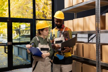 Çeşitli işçiler, küçük ölçekli bir depoda, karton kutuları e-ticaret teslimatı, toptan sevkiyat ve perakende ürün dağıtımı için doğru envanteri sağlıyorlar..