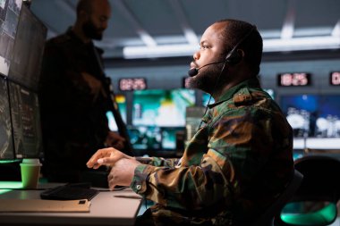 Askeri ajan mikrofon kullanıyor ve cephede savaşan komutanlara bilgi veriyor. Operasyon üssündeki askerlere istihbarat sağlayan Afro-Amerikan ordu uzmanı.