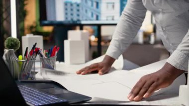 Afrika kökenli Amerikalı müteahhit masanın mimari planlarını inceliyor inşaat projesinin onaylanması için imar düzenlemelerini gözden geçiriyor. Site hazırlama ana planı ve altyapısı. Kamera A.