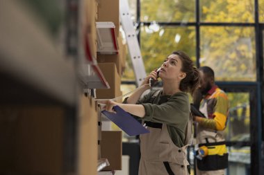 İşçi, envanter kontrolü, paket ambalajı ve e-ekommerce için sevkiyat hizmeti lojistiğini yönetmek için küçük bir iş yerindeki sabit hatlı telefona cevap veriyor. Merkez tesisi arıyor..