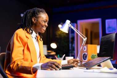 Cheerful engineer writes code on laptop while in apartment office, feeling excited after being successful. Overjoyed programmer celebrating fixing database errors while working from home