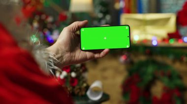 Noel Baba gibi giyinmiş biri, krom tuşlu akıllı telefondan çocukların mektuplarını okuyor. Yılbaşı karakterini canlandıran kıdemli adam izole edilmiş cep telefonu ve kamera kullanarak çocuklara cevap veriyor.