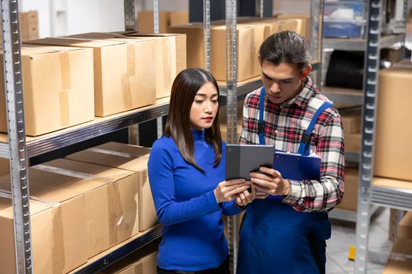 Asyalı çalışanlar bir depoda kaset kutuları ve eşyaları düzenliyor, küçük bir yerel markanın perakendecisi üzerinde çalışıyorlar. Depodaki envanter ve teslimat işlerini yürüten personel..