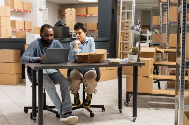 Two employees navigate order fulfillment and inventory management, shipping area of this small business highlights teamwork and operational efficiency. In house product handling.