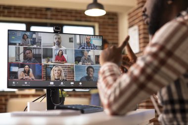 Serbest çalışan siyahi bir adam sanal giyim sırasında oturma odasında oturur ve küresel profesyonellerle fikirler sunar. Afrikalı Amerikalı erkek girişimci video çağrısında iş arkadaşlarıyla konuşuyor.