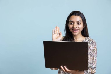 Mutlu Hintli kız stüdyodaki çevrimiçi video konferansında selam veriyor, arkadaşları ve ailesiyle iletişimde kalmak için laptop kullanıyor. Günlük modern insan video bağlantısı, pozitif ruh hali..