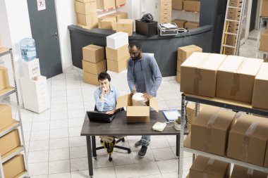 Multiethnic staff members overseeing storage and order fulfillment, ensures hand packing and distribution for a small business. Employees team supporting local storehouse logistics.